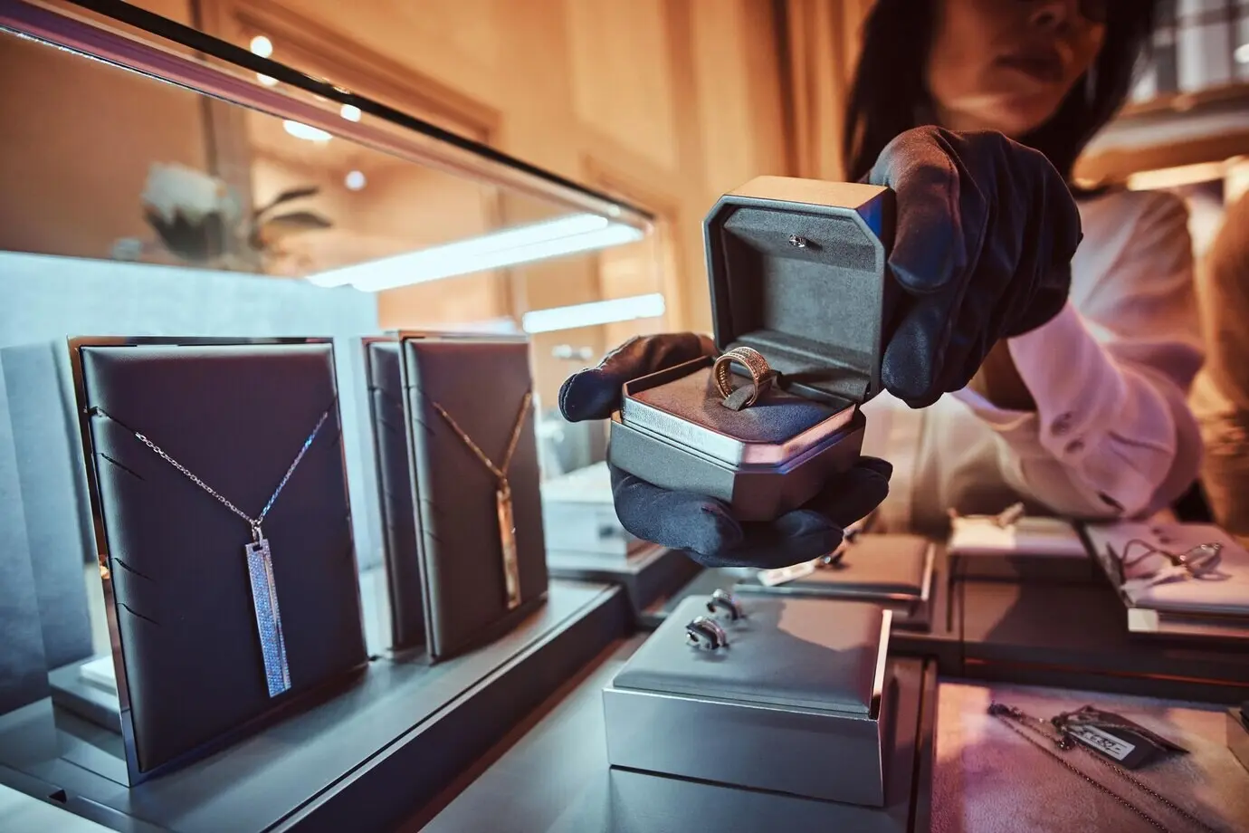 A female assistant displays an exclusive gold ring in a luxury jewelry store.